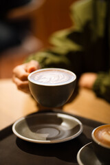 The morning sunlight falls on the table, beautiful shadows appear. Delicious breakfast.Women's hands hold a cup of hot latte coffee.	