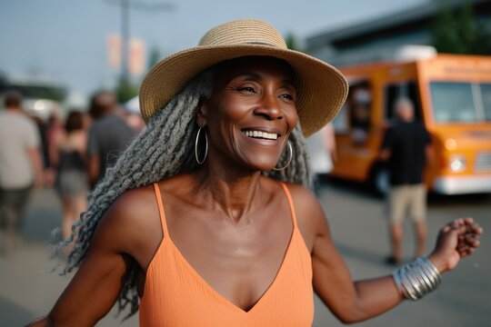 Elderly african female smiling outdoors in sun hat at street festival