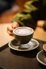 The morning sunlight falls on the table, beautiful shadows appear. Delicious breakfast.Women's hands hold a cup of hot latte coffee.