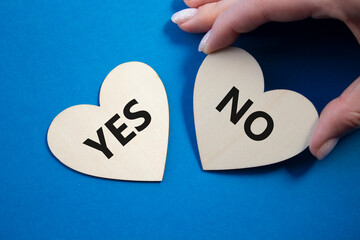 Yes or No symbol. Concept word Yes or No on wooden hearts. Businessman hand. Beautiful blue background. Business and Yes or No concept. Copy space