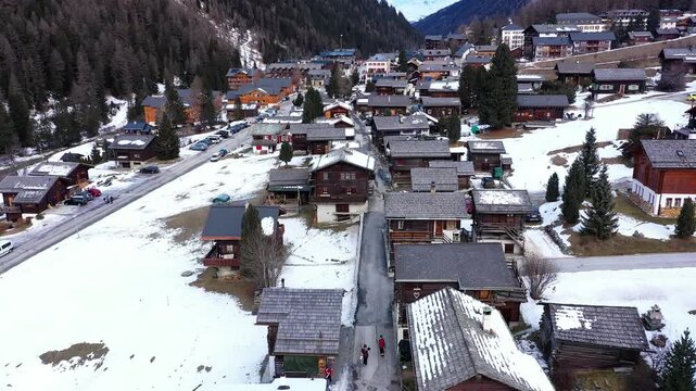 Aerial view of Zinal village nestled amid the towering, snow-dusted Alps, a contrast of rustic wooden chalets and the stark, majestic peaks, Anniviers, Valais, Switzerland.