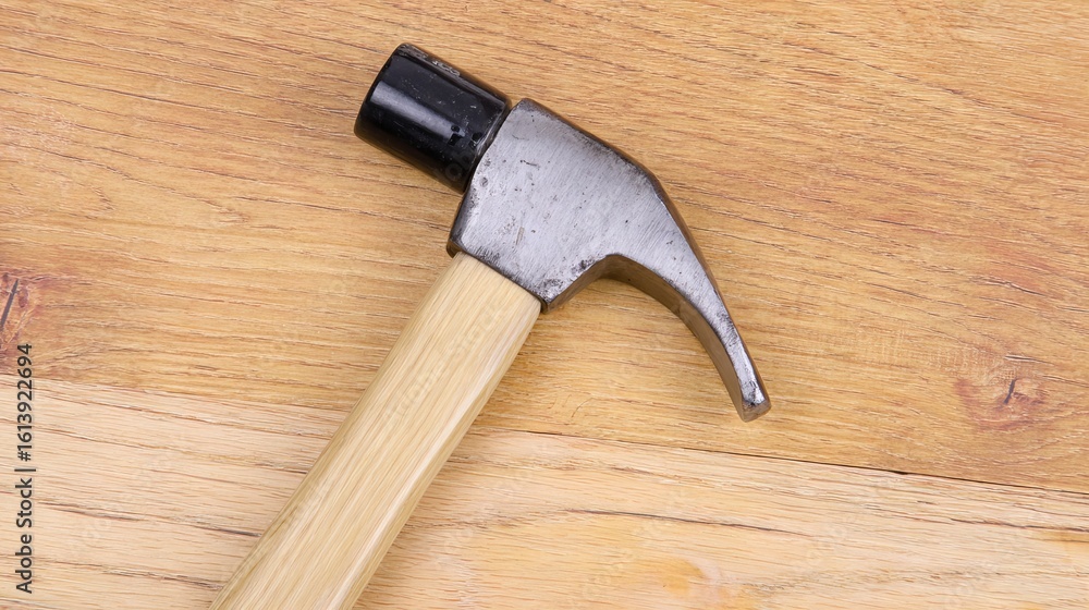 Poster hammer with a wooden handle resting on a wooden surface, showcasing the tool's design and craftsmans