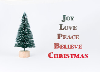 Miniature Christmas tree decoration with inspirational words joy, love, peace, believe, and...