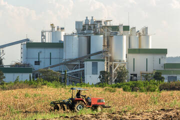 Ethanol industrial refinery with farm tractors in the foreground