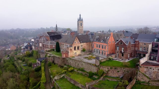Aerial view of Thuin's medieval cityscape, showcasing its historic tower, old buildings, and terraced landscapes under a soft, overcast sky, Thuin, Wallonia, Belgium.