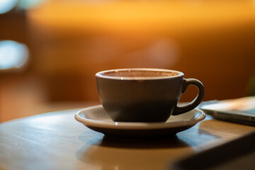 Side view of hot latte coffee a black cup on wooden table.