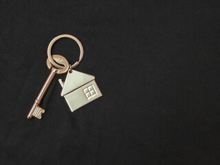 Hand holding a silver key with house shape keychain. Housing and property investment concept. House key.