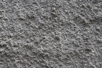Textured gray wall surface shows various patterns and imperfections due to weathering and aging in...