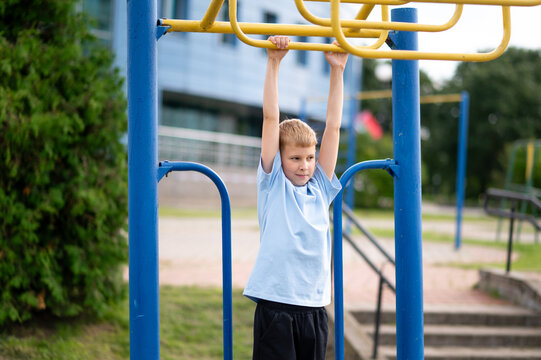 Teen boy training on monkey bars in summer park