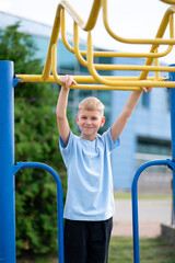 Teen boy training on monkey bars in summer park