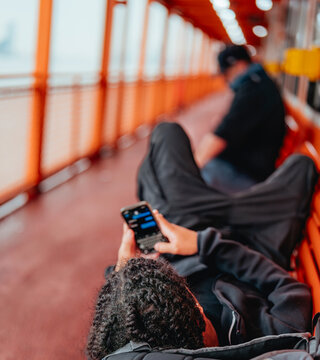 young man lying on a ferry seat chatting on his cell phone