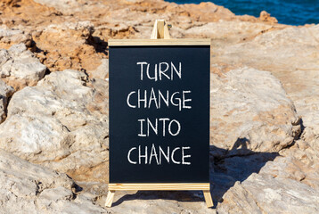 Turn change into chance symbol. Concept words phrase Turn change into chance on beautiful black blackboard. Beautiful stone blue sea background. Business Turn change into chance concept. Copy space.