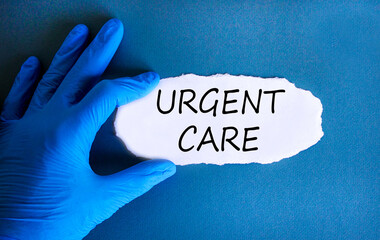 Urgent care symbol. Concept words Urgent care on beautiful white paper. Doctor's hand in blue medical glove. Beautiful blue background. Medical healthy lifestyle urgent care concept.