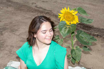 A young attractive woman sitting  near sunflower