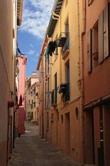 Fototapeta premium Colourful but deserted narrow street (Rue de la Liberté) in Port d’Avall, Collioure, Pyrénées-Orientales, Occitanie, France