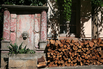Woodpile ready for winter, and ornamental marble fountain, Place de la Bouquerie, Lagrasse,...
