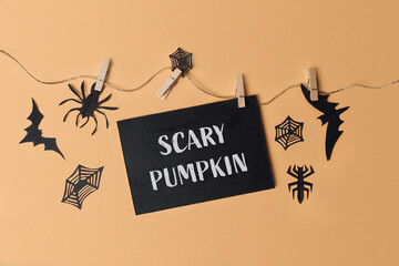 Halloween decoration with scary pumpkin sign and black paper cutouts on orange background