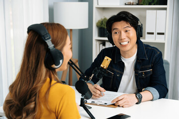 Smiling radio influencer host wearing headphone interviewing woman speaker sharing information to...