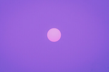 Minimalistic pink sun on purple sky.