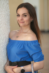 Portrait of a young beautiful long-haired girl in a blue dress in an urban environment in summer.