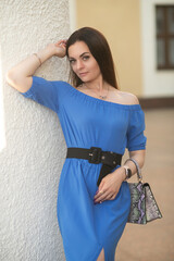 Portrait of a young beautiful long-haired girl in a blue dress in an urban environment in summer.