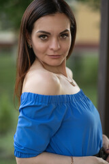 Portrait of a young beautiful long-haired girl in a blue dress in an urban environment in summer.