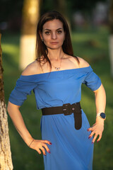 Portrait of a young beautiful long-haired girl in a blue dress in an urban environment in summer.
