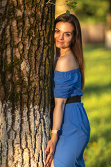 Portrait of a young beautiful long-haired girl in a blue dress in an urban environment in summer.