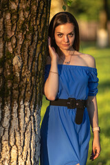 Portrait of a young beautiful long-haired girl in a blue dress in an urban environment in summer.