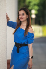 Portrait of a young beautiful long-haired girl in a blue dress in an urban environment in summer.