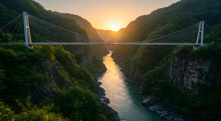 Suspension bridge spans lush mountain valley at sunset