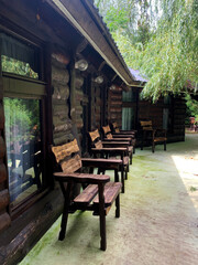 Obraz premium Wooden outdoor furniture in a cozy forest guesthouse or camping setting. Surrounded by trees and greenery. Rustic, peaceful and natural environment, perfect for relaxing in nature.