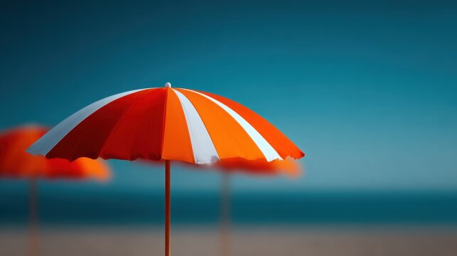 A beach scene with three umbrellas and a blue sky