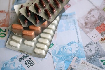 Brazilian reais banknotes and medicine pills. Brazil real money and drugs lies on table