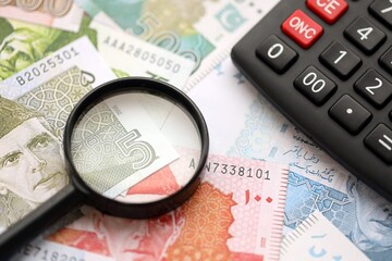 Pakistan rupees banknotes and calculator with magnifying glass. Pakistan money bills calc with loupe