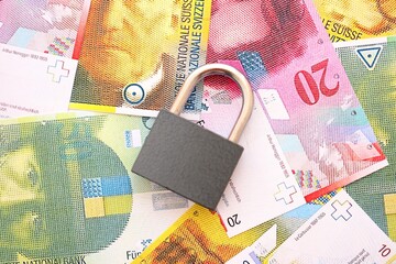 Swiss franc banknotes and padlock. The current francs money bills with lock lies in big amount