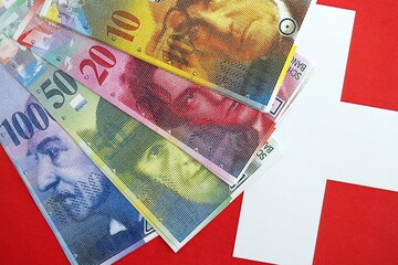 Swiss franc banknotes and flag. The current francs money bills lies on flag in big amount