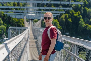 A young man walks on a suspension bridge in a skypark in Sochi, summer travel and entertainment.
