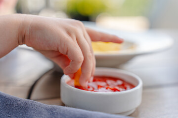 Little girl child eats French fries with ketchup in a cafe on the street.