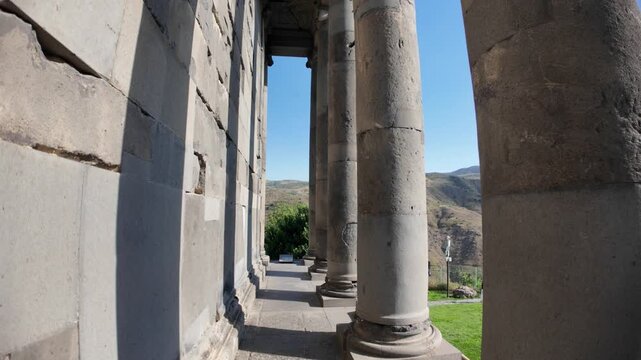 Sunlight illuminating the colonnade of Garni Temple highlights the intricate Hellenistic architecture while framing a picturesque landscape in Armenia