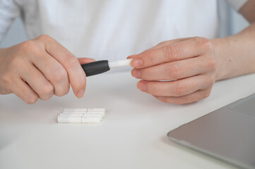 A woman inserts a cigarette stick into a tobacco heating system. Electronic cigarette.