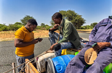 social worker with the phone checking entrepreneurs, donkey cart on the road, africa water shortage, people carry water between villages with plastic containers