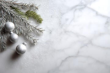 Elegant Christmas composition with silver ornaments and frosted fir branches on a white marble background, offering festive copy space.