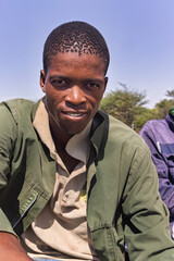 africa village, portrait head and shoulders of young african man profile view , outdoors against...