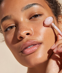 Young African American woman massaging her face with a stone roller for skin care