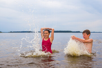 Children, boy and girl in red swimsuit swimming in the lake