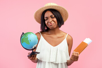 Travel ban during coronavirus. Upset black woman holding plane tickets, passport and globe over...