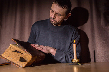A man, European, 49 years old, reads an old book. Everyday life of the population of Russia.