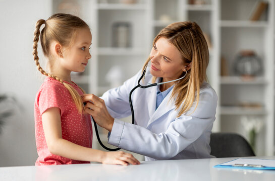 Female doctor checking lungs of little girl during medical checkup in clinic, friendly pediatrician woman using stethoscope to examine breathing and heartbeat of young patient, closeup shot