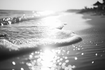Calm ocean waves on sandy shore during sunset. Beach scene with gentle ripples and starbursts of light reflecting off water.